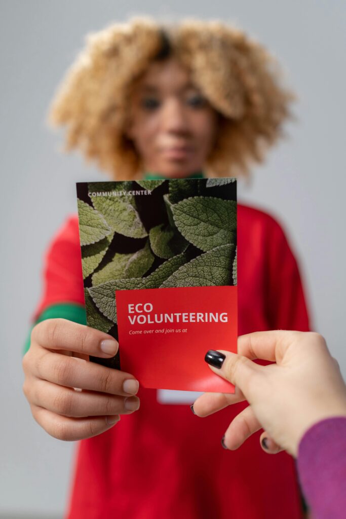 join us Close-up of a person handing out an eco volunteering flyer, promoting community service.