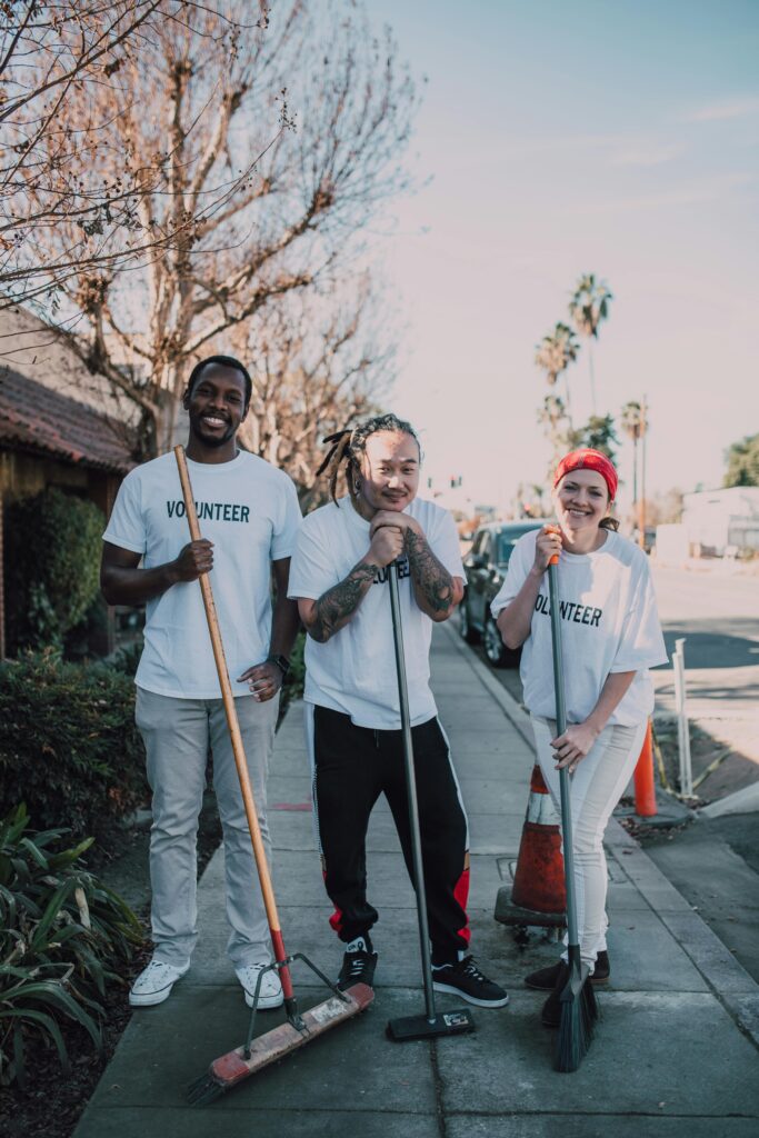 A group of cheerful volunteers cleaning a sidewalk on a sunny day, promoting community service. A group of cheerful volunteers cleaning a sidewalk on a sunny day, promoting community service.